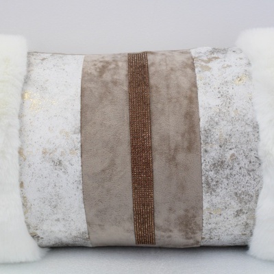 Almofada retangular com pele sintética branca e tecidos bege e branco com padrão abstrato.