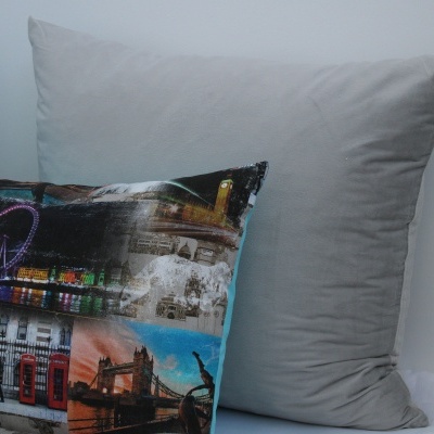 Almofadas decorativas, uma com estampas urbanas coloridas e outra cinza lisa