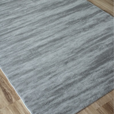 Tapete cinzento com padrão abstrato sobre chão de madeira clara