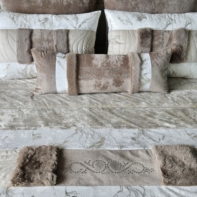 Almofadas e manta de cama castanhas e bege com diferentes texturas e padrões marmoreados.