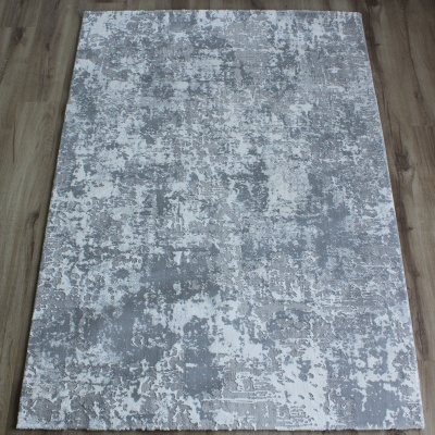Tapete cinzento claro e branco com padrão abstrato sobre chão de madeira.