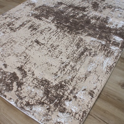 Tapete retangular bege com padrão abstrato castanho e cinza numa superfície de madeira clara