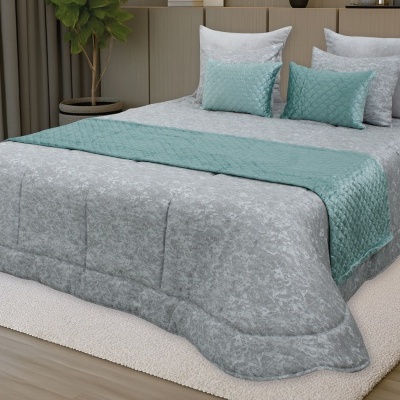 Conjunto de cama com edredão cinza e almofadas azul-turquesa em ambiente de quarto
