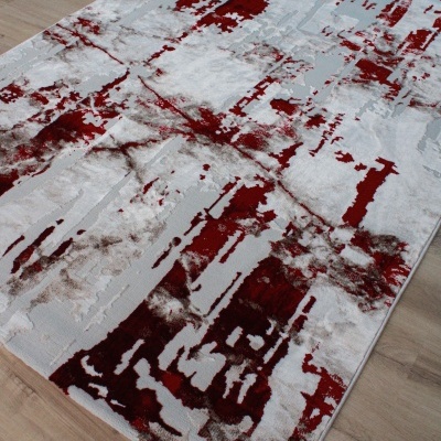 Tapete retangular com padrão abstrato vermelho, branco e cinzento sobre chão de madeira clara