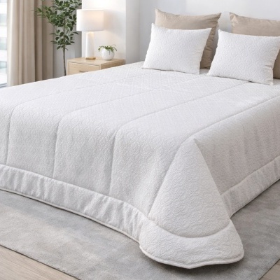 Colcha branca acolchoada com padrão floral e almofadas em cama moderna num quarto minimalista