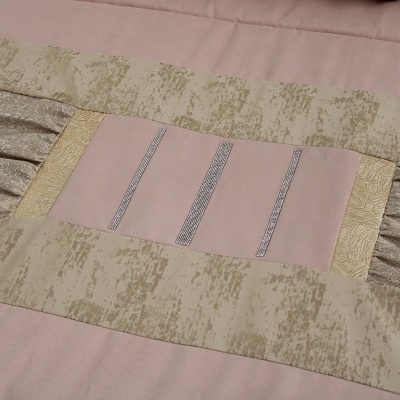 Colcha rosa claro com detalhes em bege e dourado com textura e listas verticais metálicas