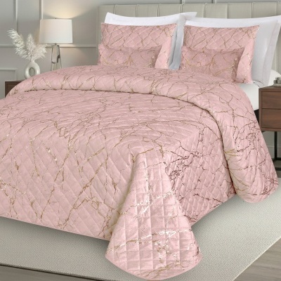 Colcha rosa com padrão dourado marmorizado e almofadas na cama.