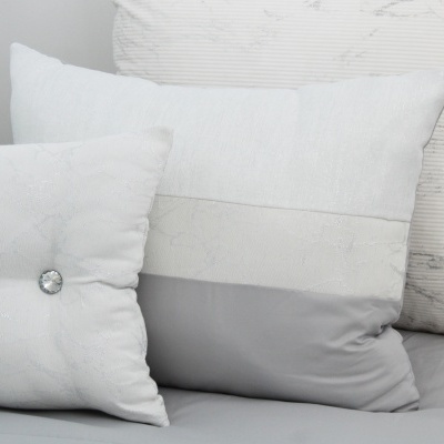 Três almofadas brancas e cinza com diferentes texturas e botão decorativo
