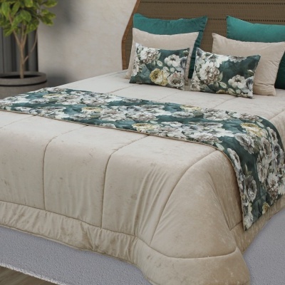 Cama com edredão bege e almofadas verdes e florais