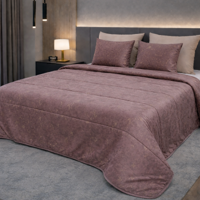 Conjunto de cama com edredão e almofadas cor malva com padrão dourado numa cama com cabeceira cinza