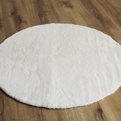 Tapete oval branco felpudo sobre chão de madeira clara