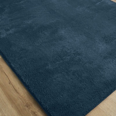 Tapete azul escuro de pelo curto sobre chão de madeira clara