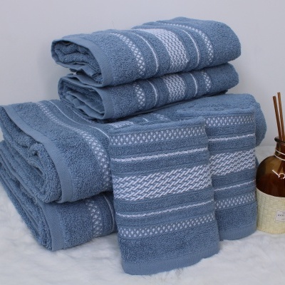 Conjunto de toalhas de banho azuis com padrões brancos e frasco decorativo castanho com palitos.