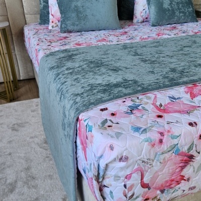 Cama com roupa de cama floral e almofadas em veludo azul esverdeado em quarto moderno