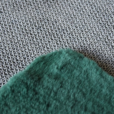 Detalhe de tecido verde felpudo sobre superfície com padrão geométrico preto e branco