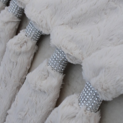 Detalhe de tecido felpudo cinza claro com anéis de strass prateados.