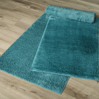 Tapete azul turquesa aveludado sobre chão de madeira clara