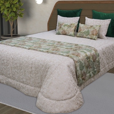 Cama arrumada com edredão bege, almofadas verdes e almofadas florais em tons verdes e castanhos