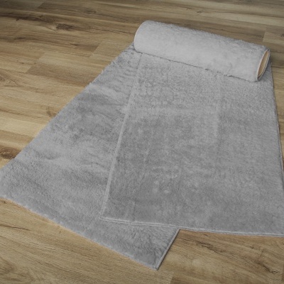 Tapete cinza claro com textura macia desenrolado no chão de madeira