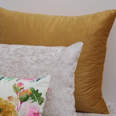 Três almofadas com veludo mostarda, padrão cinza e floral colorido