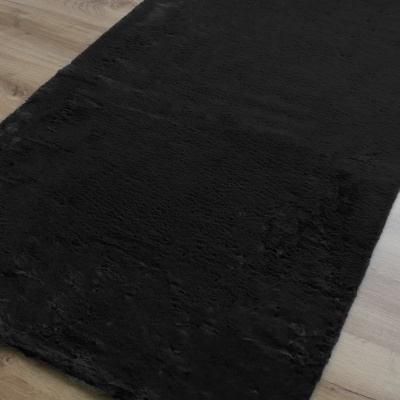 Tapete preto felpudo sobre chão de madeira clara
