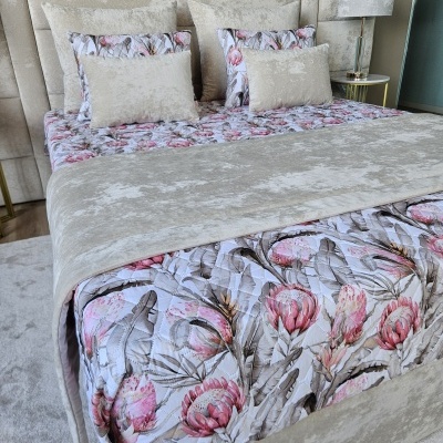Cama com colcha floral e almofadas bege em quarto moderno com abajur cinza