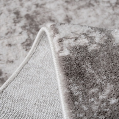Tapete felpudo cinza e branco com padrão abstrato e bordas costuradas