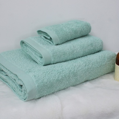 Conjunto de toalhas de banho azuis claras empilhadas junto a difusor de aromas em frasco âmbar