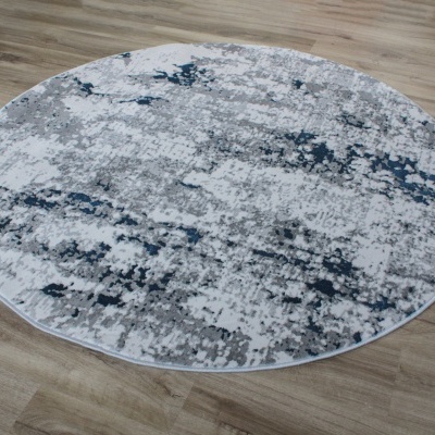 Tapete redondo com padrão cinza, branco e azul escuro em piso de madeira