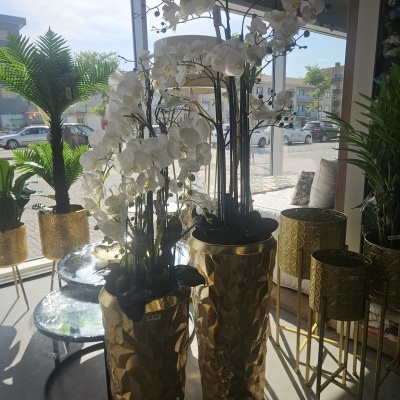 Orquídeas brancas artificiais em vasos dourados numa loja