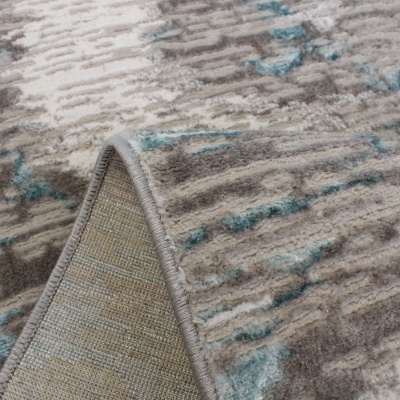 Tapete com padrão abstrato em tons bége, castanho e azul, parcialmente dobrado para mostrar o verso.