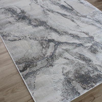 Tapete retangular cinza e branco com padrão abstrato tipo mármore sobre chão de madeira