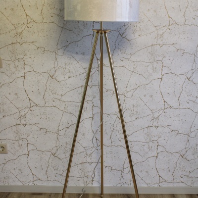 Candeeiro de pé dourado com cúpula branca e fundo de parede marmoreada