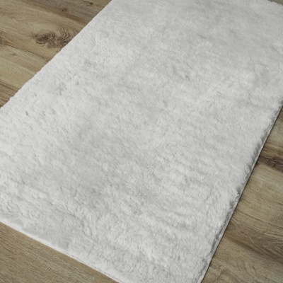 Tapete branco felpudo sobre chão de madeira clara