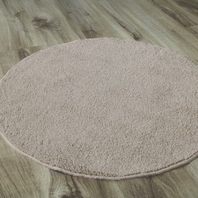 Tapete redondo bege claro sobre chão de madeira clara
