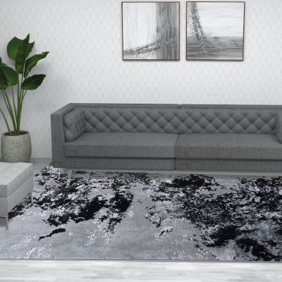 Sala com sofá cinzento acolchoado, tapete manchado cinzento e preto, banco cinzento, planta em vaso e quadros abstratos na parede