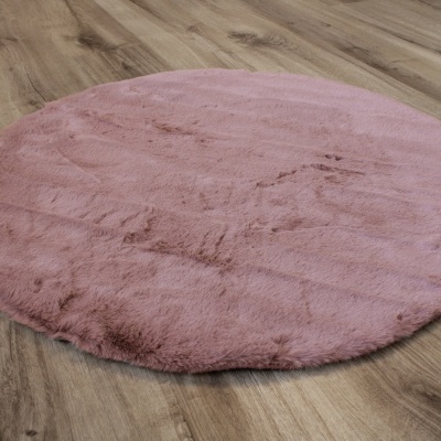 Tapete redondo rosa peludo sobre chão de madeira