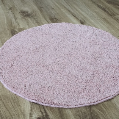 Tapete redondo rosa claro em chão de madeira clara