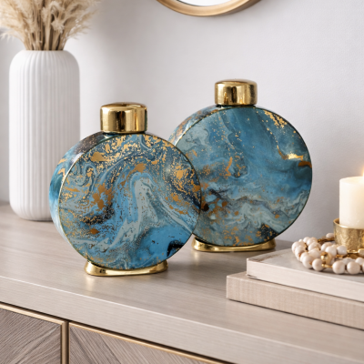 Dois jarros decorativos redondos azul marmoreado com detalhes dourados em móvel de madeira