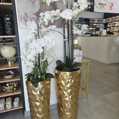 Vasos dourados com orquídeas artificiais num interior de loja