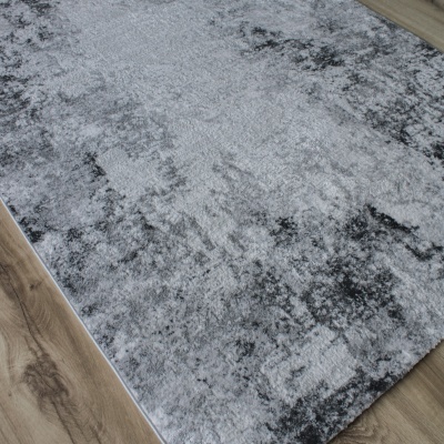 Tapete cinza e preto com padrão abstrato em chão de madeira