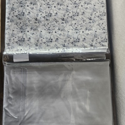 Conjunto de têxteis para cama embalados em plástico transparente com padrão floral e cor cinza sólido