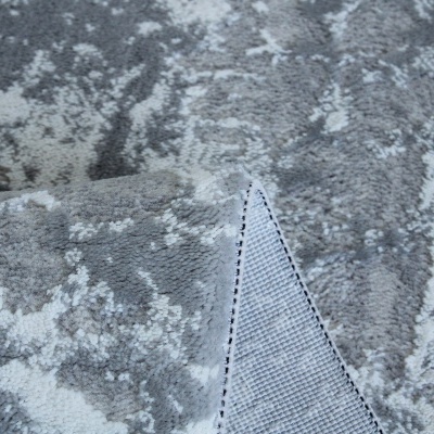 tapete cinza com padrão abstrato e dobra mostrando o verso