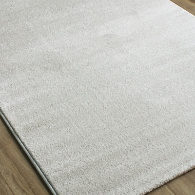 Tapete branco felpudo sobre chão de madeira clara.