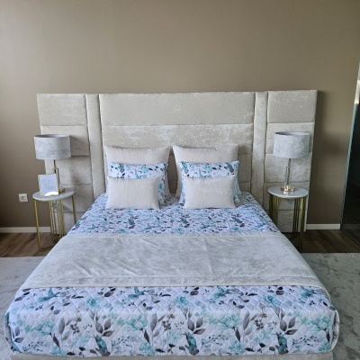 Cama estofada com cabeceira alta cinza claro e roupa de cama floral