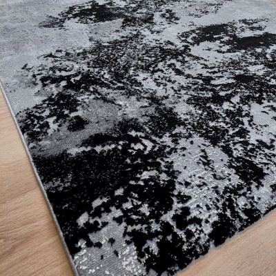 Tapete cinza e preto com padrão abstrato sobre chão de madeira