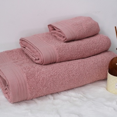 Conjunto de toalhas rosa empilhadas ao lado de difusor de ambiente