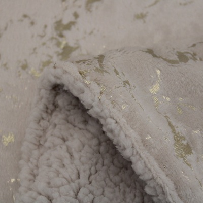 Detalhe de manta bege com padrão dourado e interior felpudo