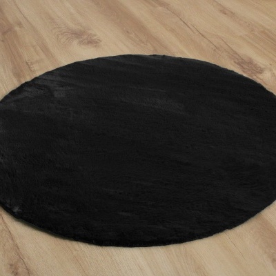 Tapete redondo preto sobre chão de madeira