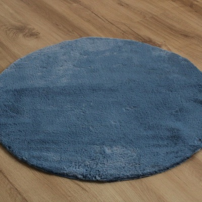 Tapete redondo azul de pelo curto numa superfície de madeira clara